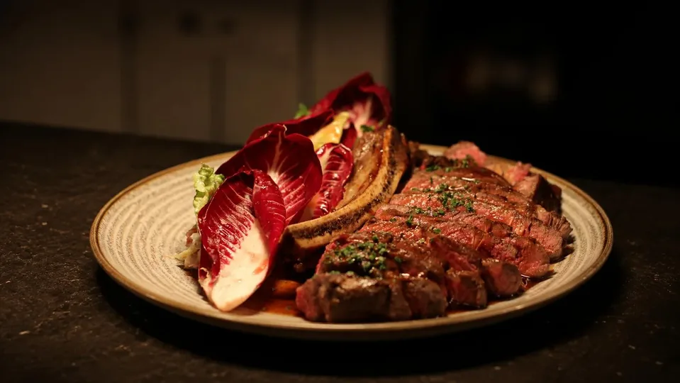 Côte de boeuf geserveerd met radicchio salade en eendenvet aardappels